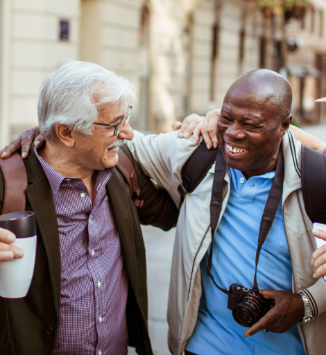 2 older gentleman greeting each other whilst out in a town.