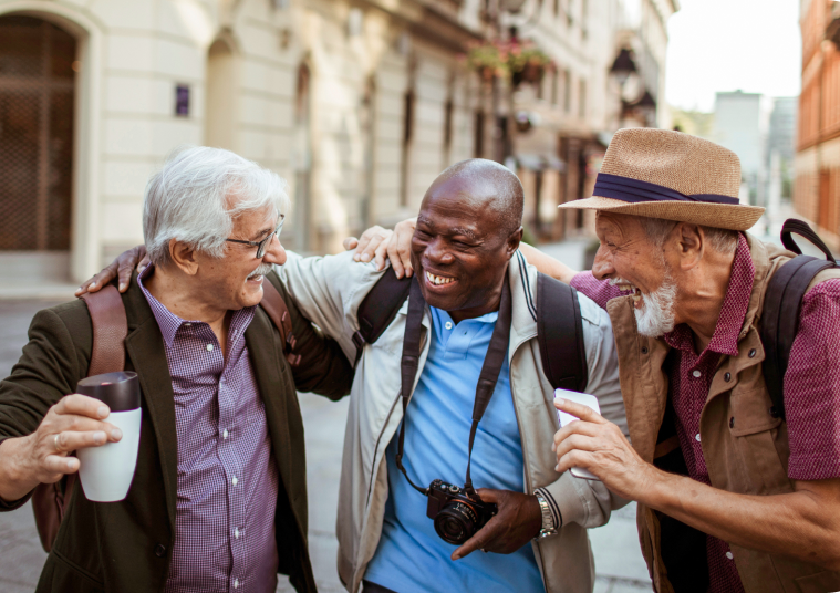 3 older gentleman greeting each other whilst out in a town.